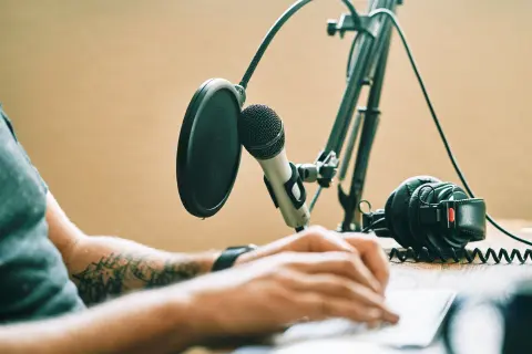 Someone taking notes at a computer with a microphone on their desk